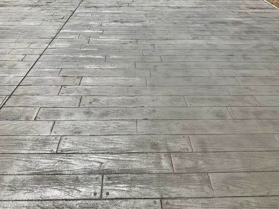 A concrete surface, expertly crafted by our Apache Junction concrete services, is designed to resemble wooden planks. Featuring narrow grooves and slight texture variations, it creates the look of a wooden floor. Contact us today for a free quote!.